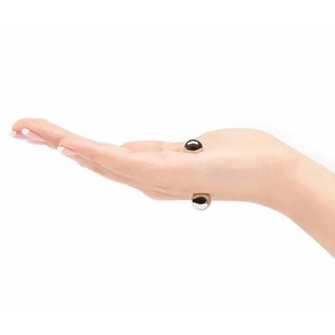 Flache Hand in Seitenansicht mit zwei silbernen Kugeln an Handrücken und Handfläche.
