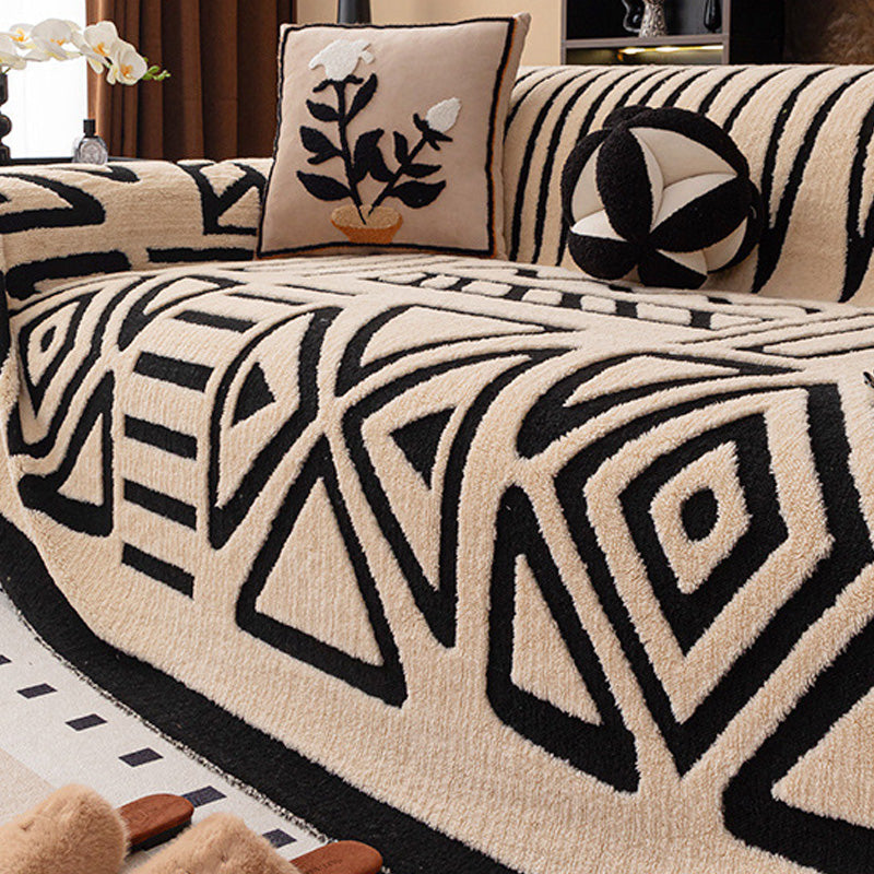 Beiger Überwurf mit schwarzem geometrischem Muster aus Dreiecken und Rauten, dazu Blumenkissen und rundes Kissen 17