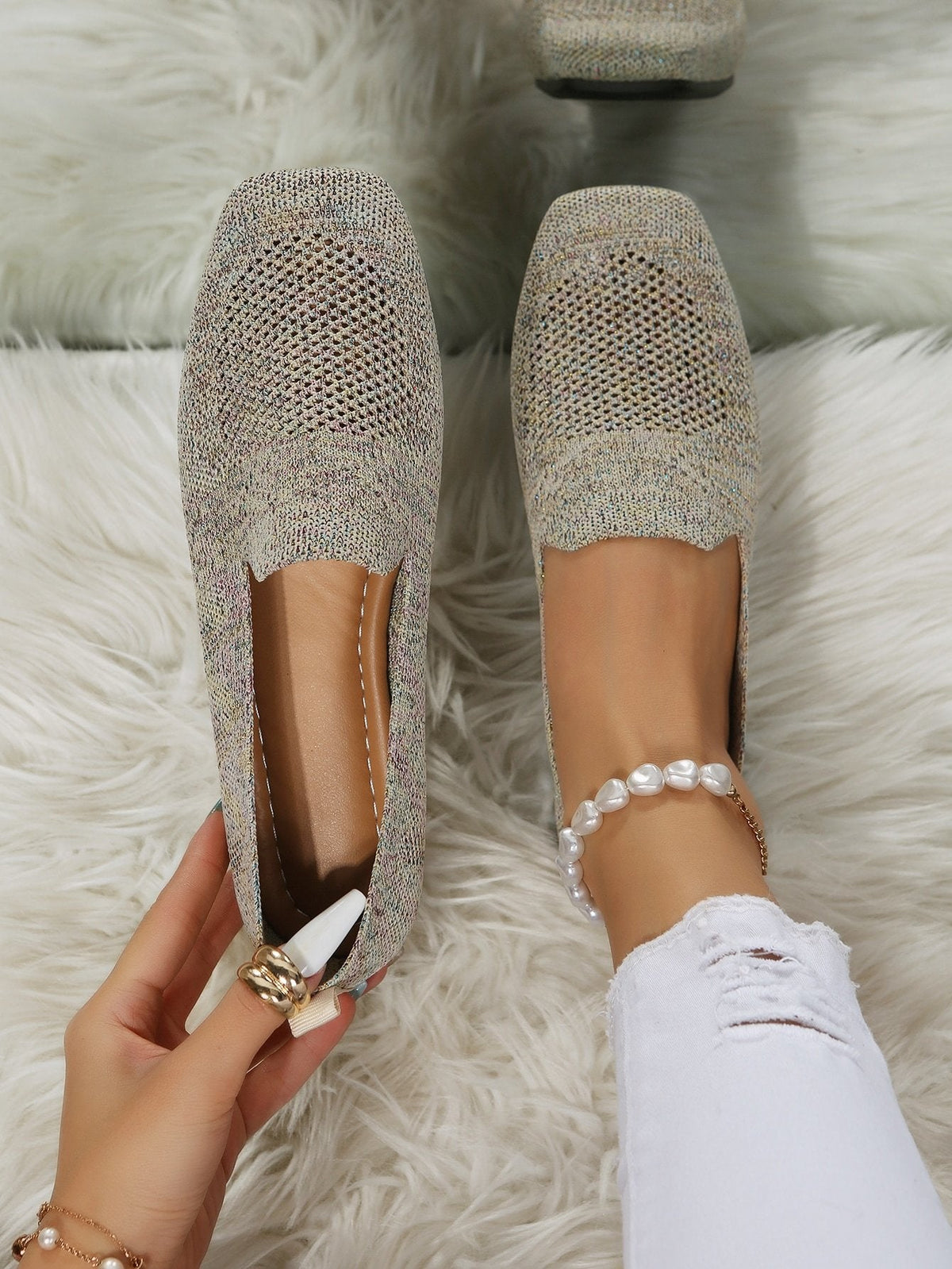 Draufsicht auf ein Paar beige-meliertes Slip-On-Modell mit luftigem Netzeinsatz und eckiger Spitze, ein Schuh am Fuß, einer in der Hand gehalten. 21