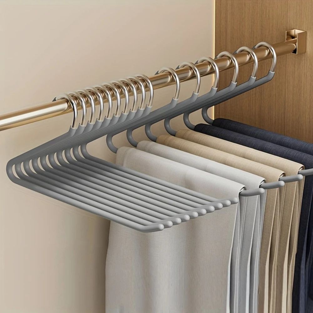 Graue Hosenbügel an einer Kleiderstange im Schrank, behängt mit Hosen in Beige, Hellgrau und Dunkelblau 4
