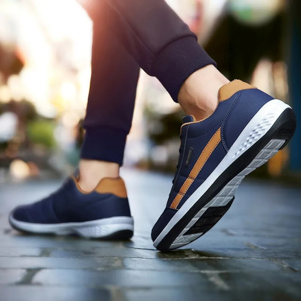 Dunkelblaue Ledersneaker mit braunem Seitenpaneel von hinten und seitlich im Schritt, mit sichtbarer profilierter Laufsohle.