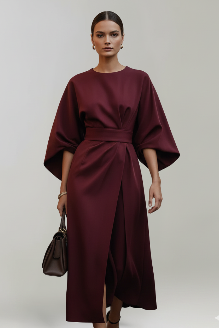 Model im weinroten Kleid mit weiten Ärmeln, Gürtel und Wickelrock mit Schlitz, dazu eine braune Handtasche 11