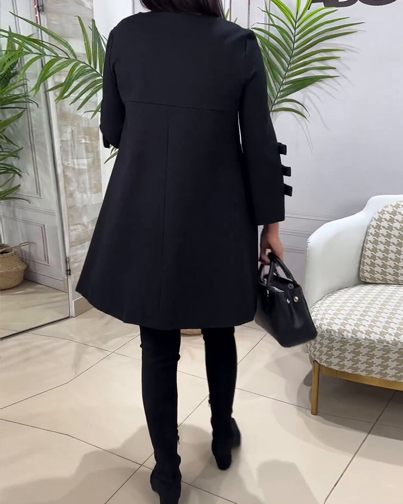 Frau in schwarzem Mantel, schwarze Hose, schwarze Tasche, moderne Inneneinrichtung.
