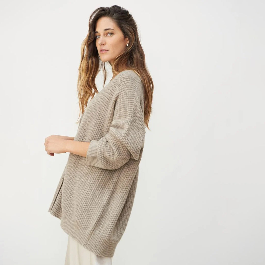 Frau in beigem Strickpullover, lässiger Stil, nachhaltige Mode, seitliches Profil.