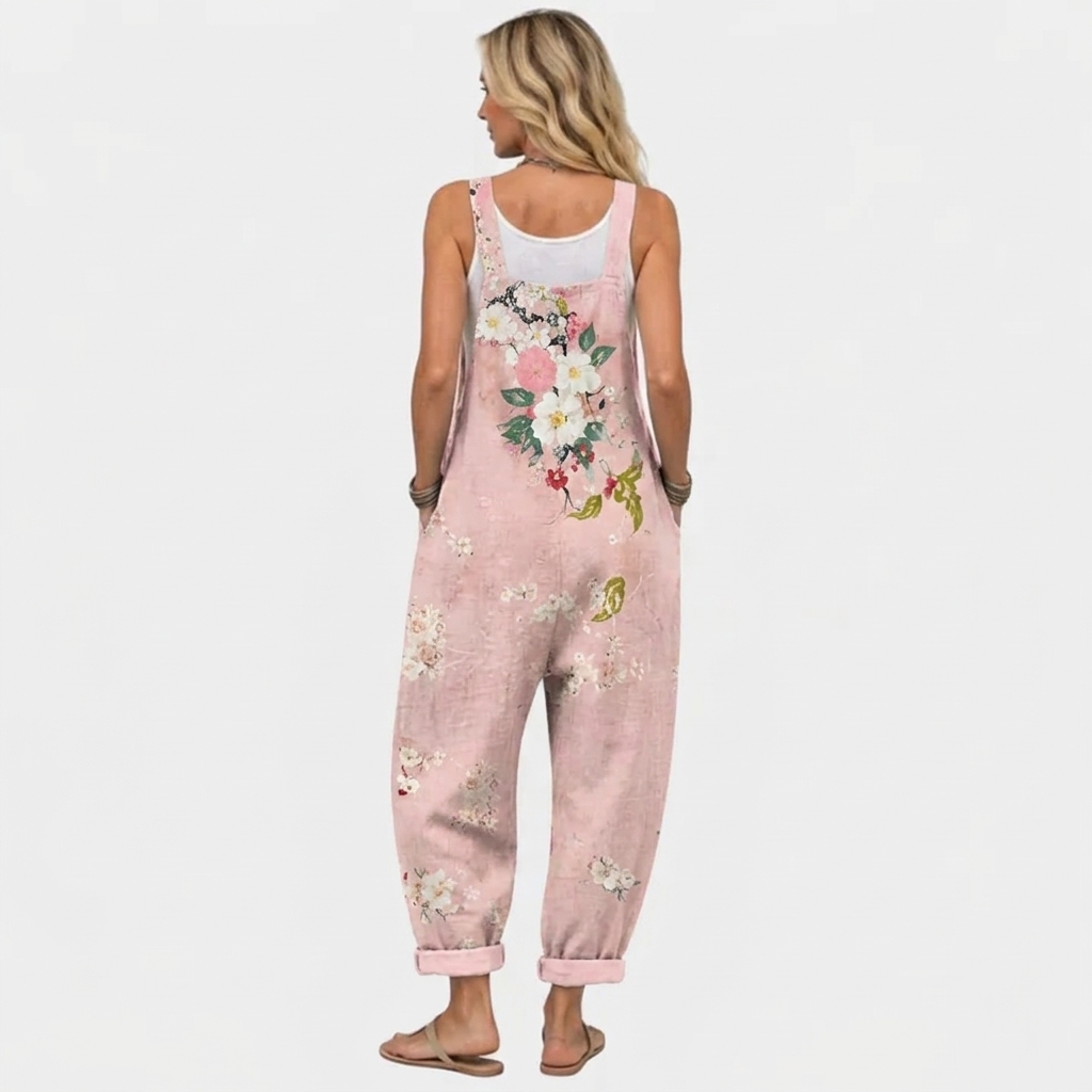 Rückansicht der Latzhose am Model mit breiten Trägern und dem Blumenmuster, das sich über den Rücken und die Beine zieht. 4