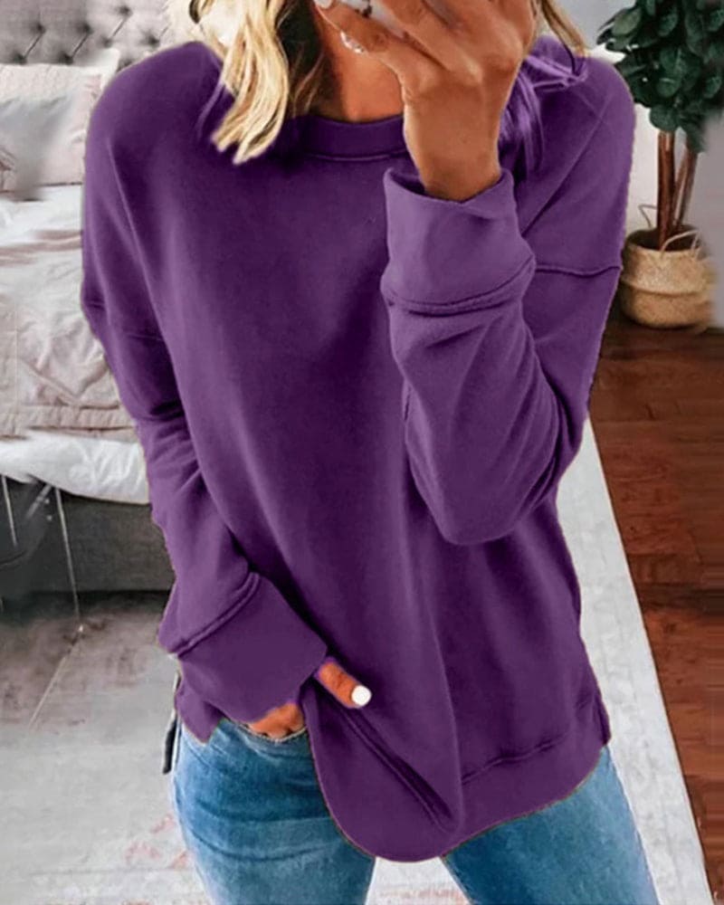 Frau in lila Pullover und blauer Jeans im Wohnzimmer, gemütliche Freizeitmode.