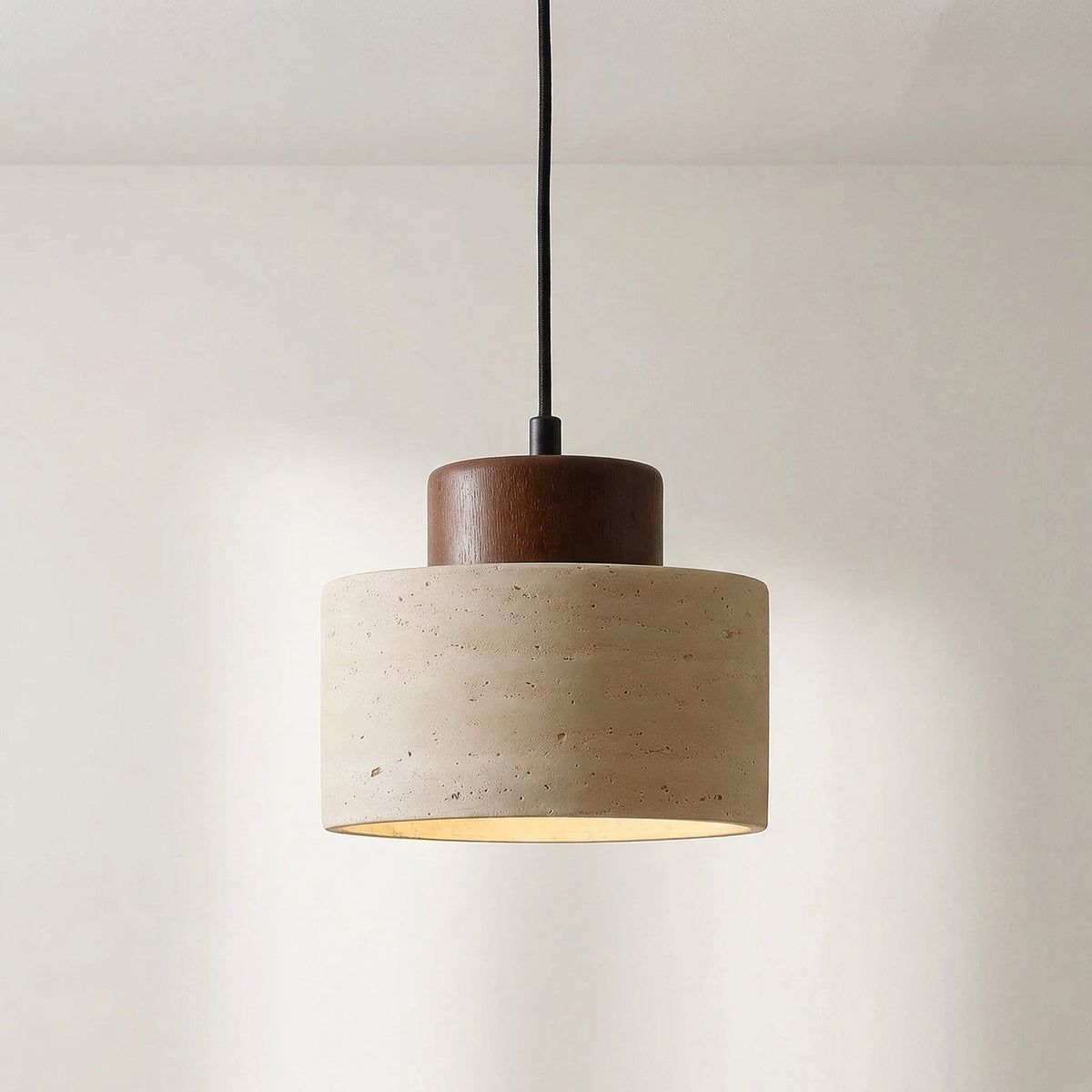 Nahaufnahme der Pendelleuchte mit dunklem Holzaufsatz und porigem, gemasertem Travertinschirm vor heller Wand 6