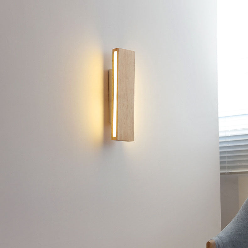 Senkrecht montierte Holz-Wandleuchte mit leuchtendem Seitenstreifen an einer Wand neben Fenster mit Jalousie und Stuhl.