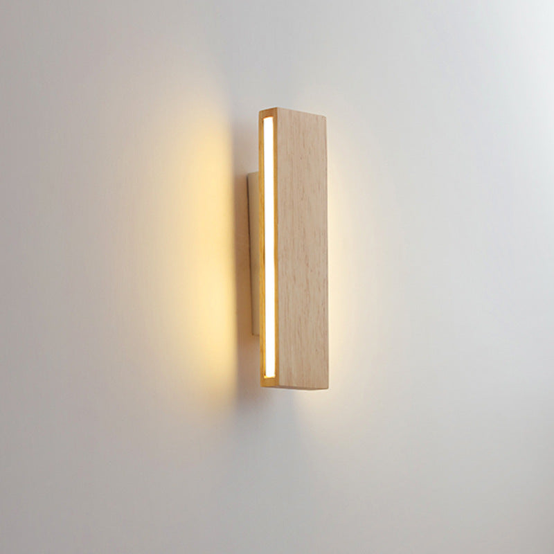 Senkrechte Holz-Wandleuchte mit seitlich leuchtendem LED-Streifen und warmem Lichtschein an der Wand.