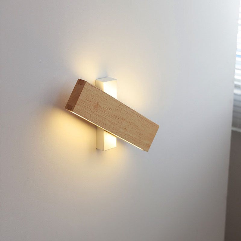 Holzbalken quer über weißer Halterung, die warmes Licht an die Wand abgibt.