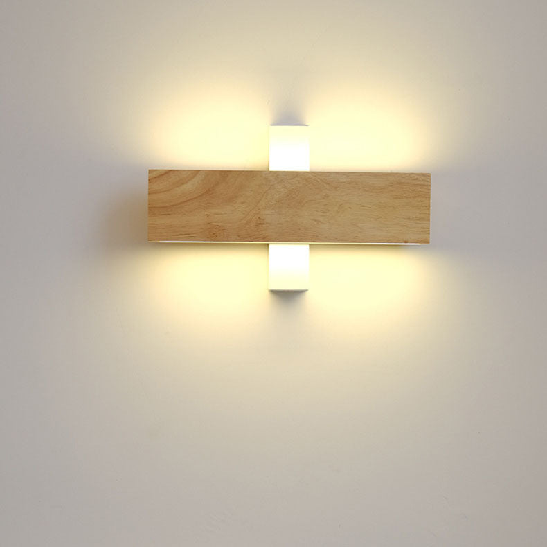 Waagerecht gedrehter Holzbalken vor weißer Halterung, die warmes Licht auf die Wand strahlt.