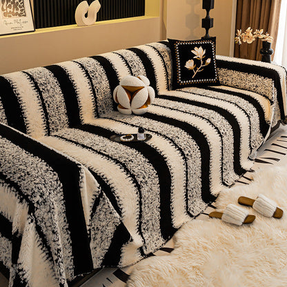 Sofa mit breit gestreiftem Plüschüberwurf in Schwarz und Creme, davor Fellteppich und Pantoffeln 9