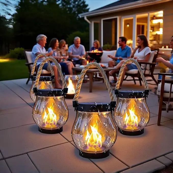 Mehrere Laternen mit Flammeneffekt auf einer Terrasse, im Hintergrund eine gesellige Runde am Abend 5
