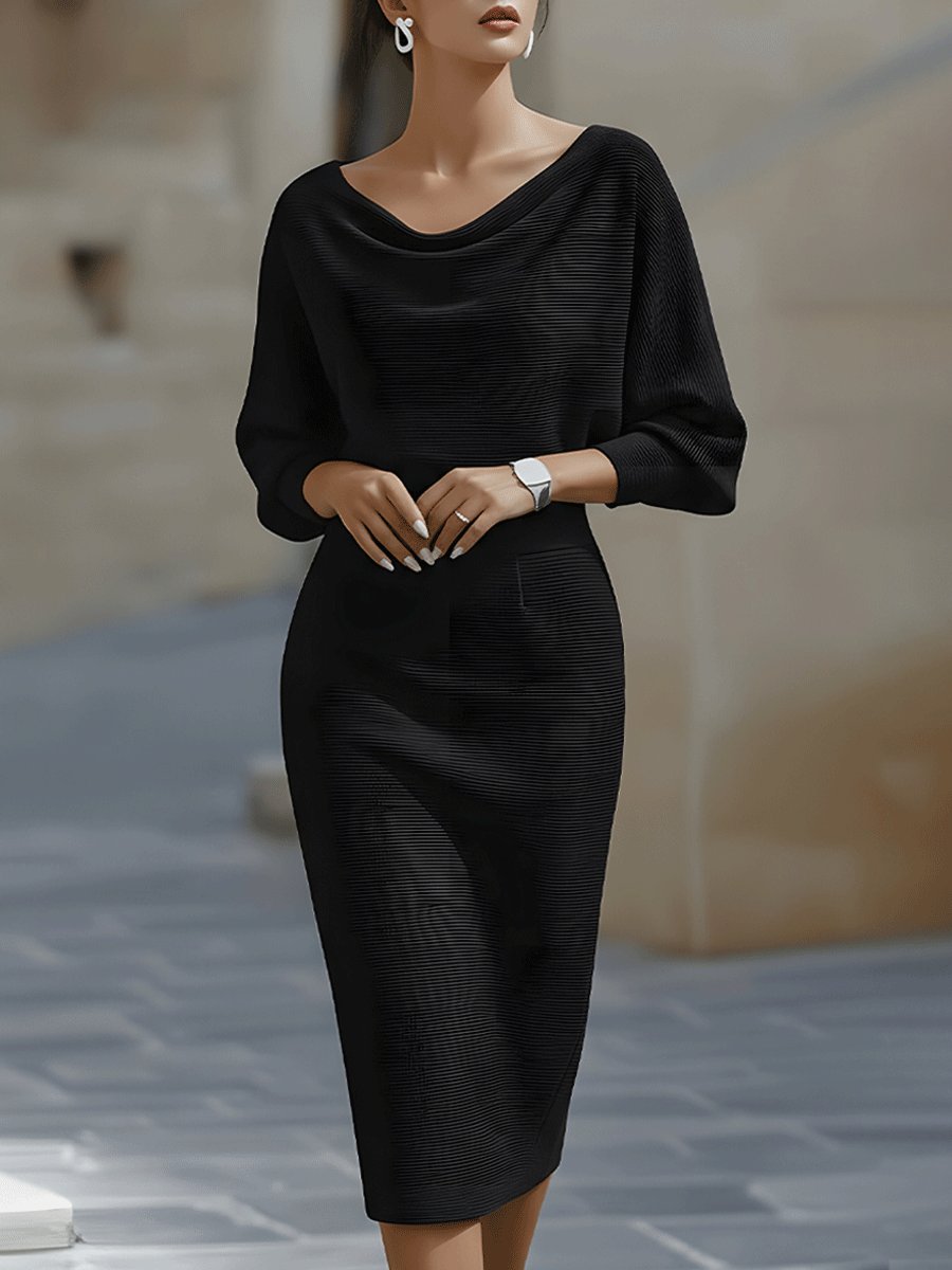Frontansicht: Model in schwarzem, fein gerippt gestricktem Midikleid mit Wasserfallausschnitt, weiten Fledermausärmeln und enger Taille, im Freien. 1