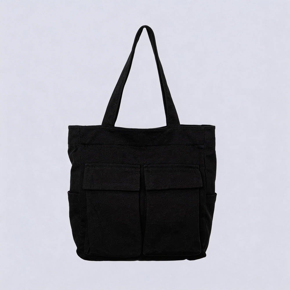 Schwarze Tote Bag aus Stoff mit zwei aufgesetzten Klappentaschen vorn und seitlichen Einstecktaschen, freigestellt vor hellem Hintergrund.