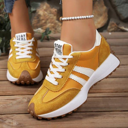 Gelbe Sneaker mit weißen Streifen, getragen auf Holzboden, vorderer Schuh in Seitenansicht, zweiter von vorn 6