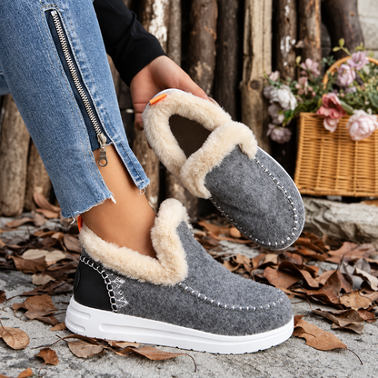 Graue Slip-On-Sneaker mit Plüschfutter, ein Schuh getragen, der andere in der Hand gehalten, sodass die Innenseite sichtbar ist. 5