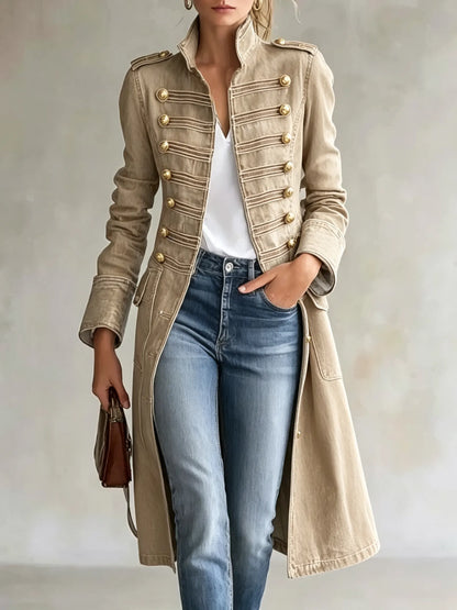 Beiger Mantel mit goldenen Knöpfen und Posamenten, offen über weißem Shirt und Jeans getragen.