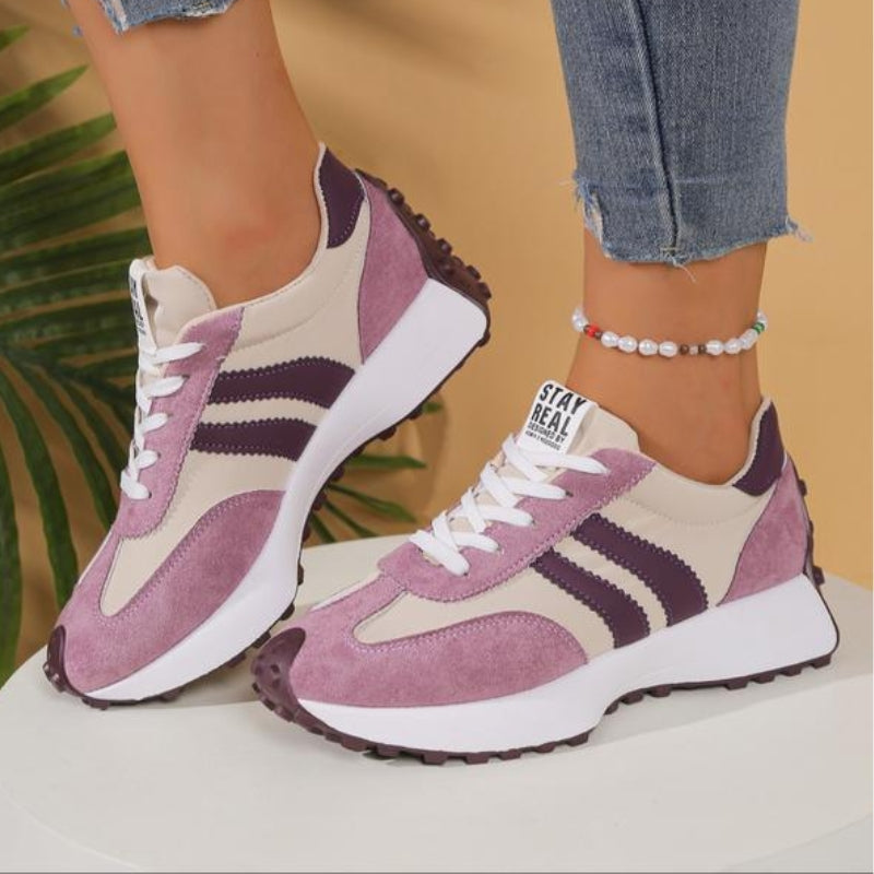 Rosa-beige Sneaker mit violetten Streifen und Plateausohle, getragen zu Jeans, Seitenansicht auf weißem Podest 12