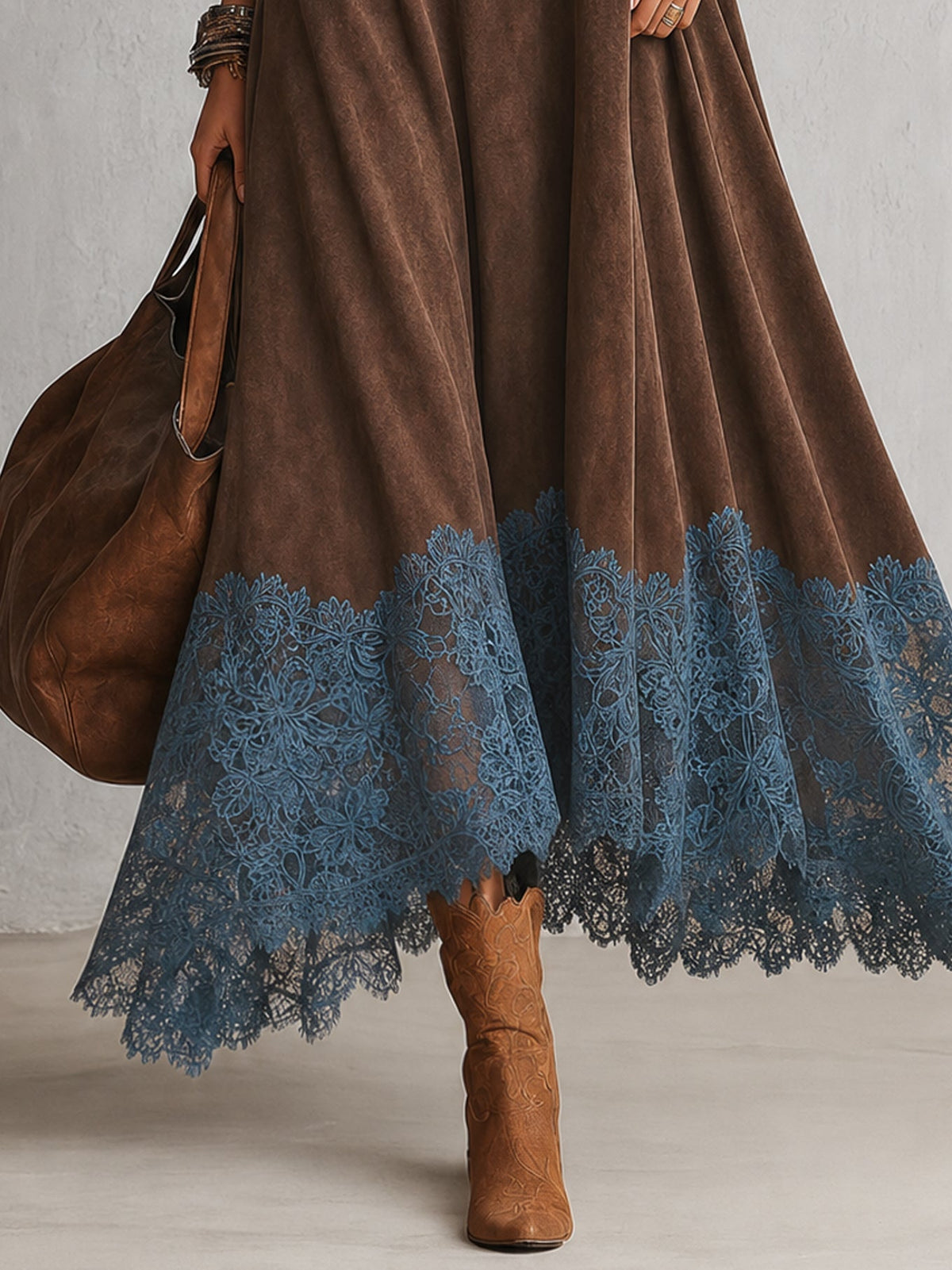 Nahaufnahme des blauen Spitzensaums am braunen Kleid, dazu Lederstiefel und Beutel 3