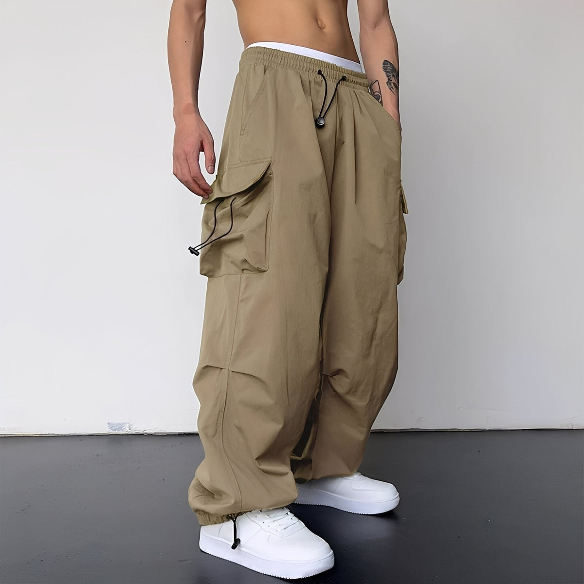 Weite Cargohose in Beige-Khaki, am Model getragen, mit großen Seitentaschen, Kordelzug und Bündchen am Saum 1