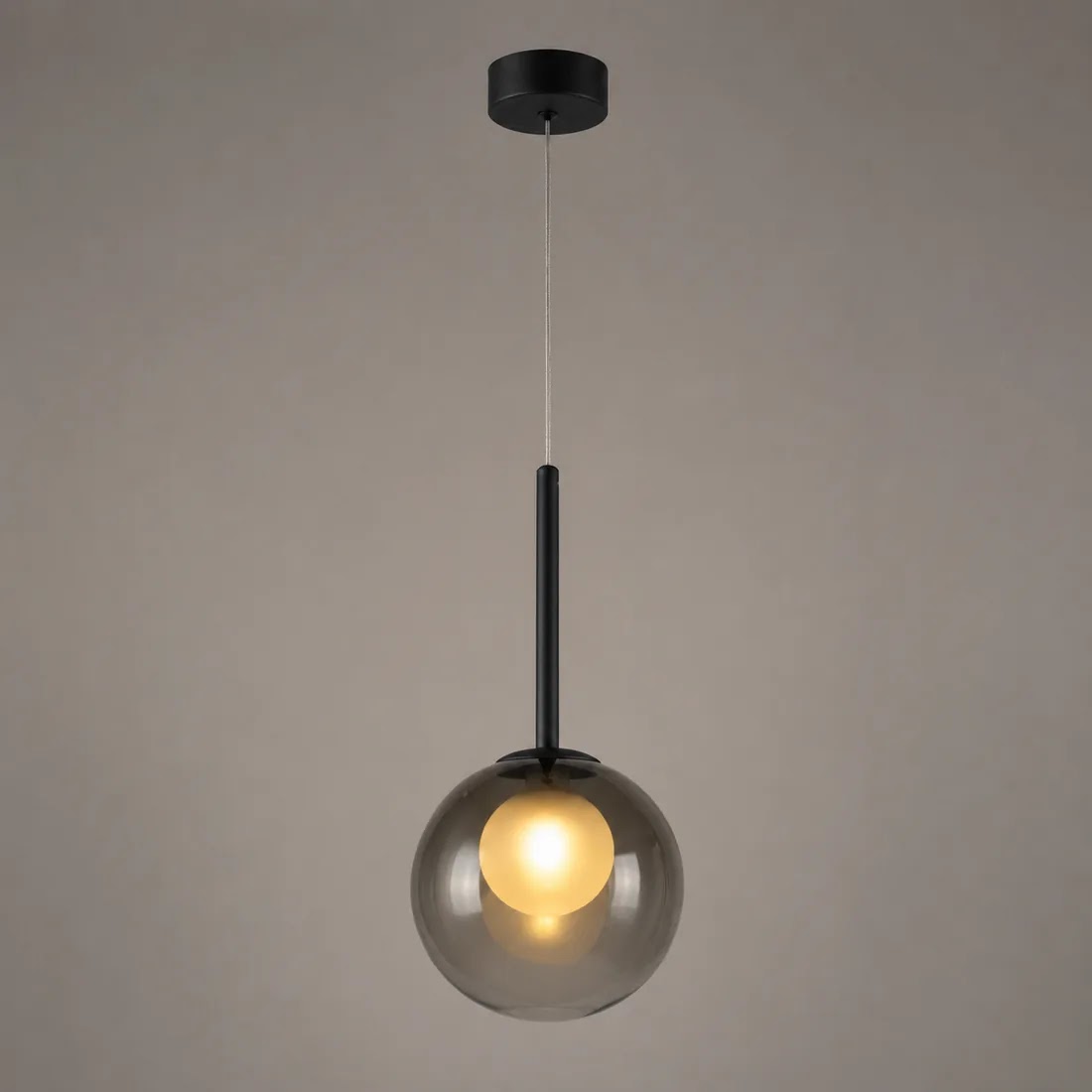 Rauchgraue Pendelleuchte mit schwarzer Stange leuchtet warm vor einer grau-beigen Wand 10