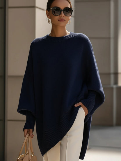 Dunkelblauer Strickponcho an einer Frau mit Sonnenbrille, Hand in der Tasche der weißen Hose 9