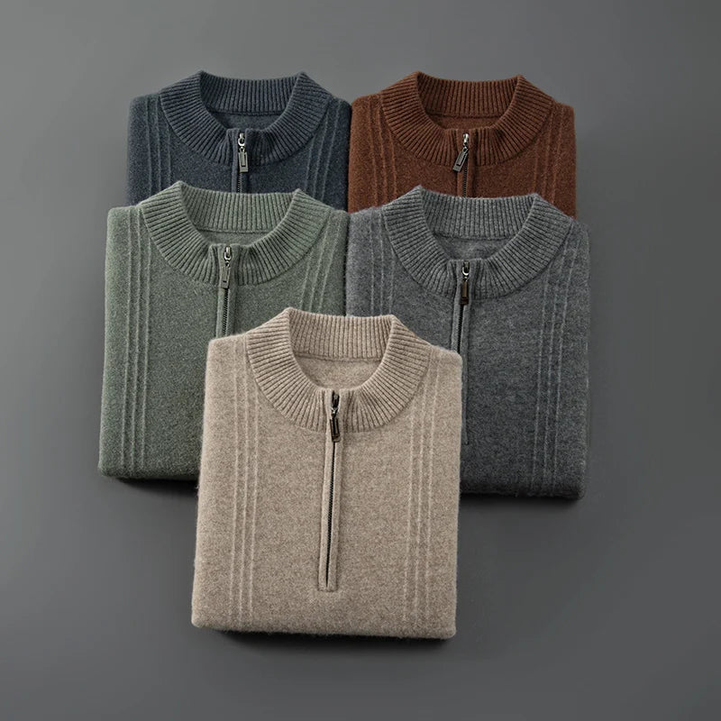 Fünf gefaltete Pullover mit Reißverschluss, verschiedene Farben, aus Wolle, auf grauem Hintergrund.
