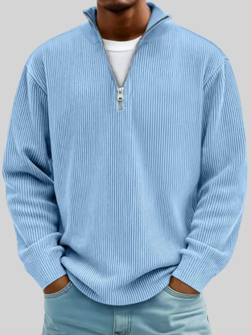 Gerippter Pullover in Hellblau mit Viertelreißverschluss, getragen von einem Model mit weißem Shirt darunter.