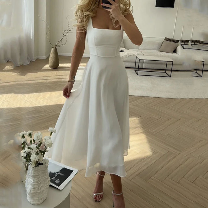 Frau in weißem Sommerkleid im modernen Wohnzimmer, Blumen in Vase, elegantes Design.