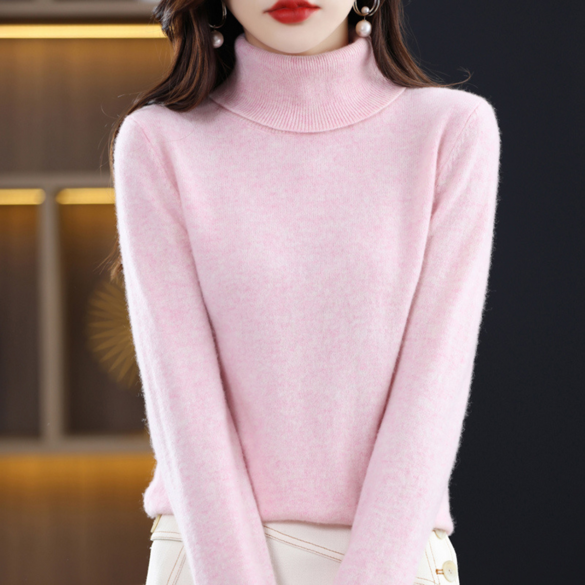 Zartrosa melierter Rollkragenpullover am Model in Frontansicht mit heller Hose.
