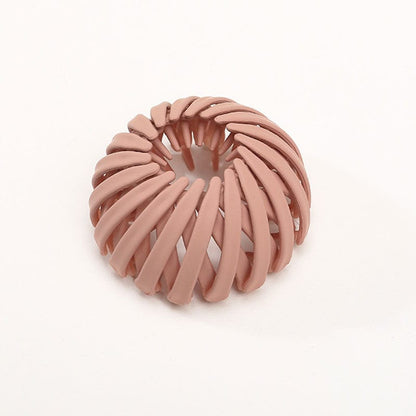 Matte Haarklammer in Terrakotta-Rosa mit spiralförmig angeordneten Rippen, einzeln vor hellem Hintergrund.