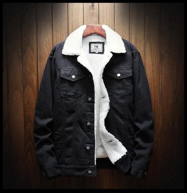 Schwarze Herren-Denimjacke mit weißem Wollfutter, warme Wintermode, hängend an Holzwand.