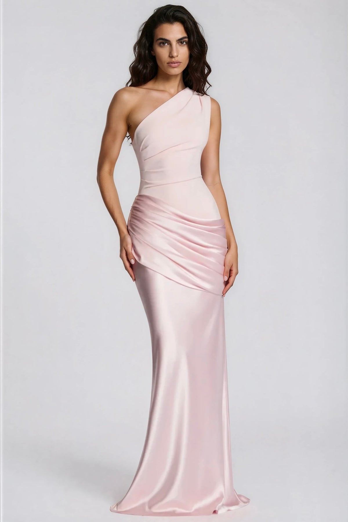Model in zartrosa Maxikleid mit einer Schulter, lockeren dunklen Wellen und glänzendem, gerafften Satinrock, Dreiviertelansicht von vorn. 30