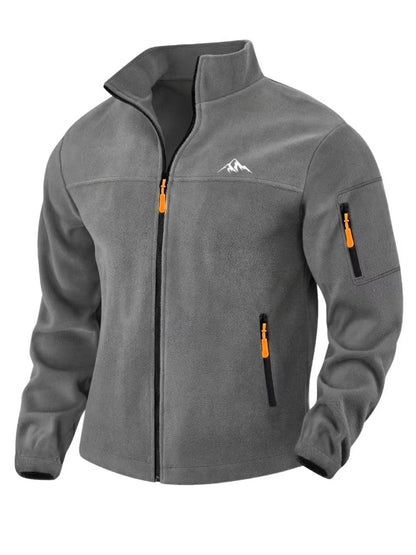 Mittelgraue Fleecejacke in Vorderansicht mit Stehkragen, orangefarbenen Zippern und Reißverschlusstasche am Ärmel 6