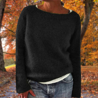Schwarzer Strickpullover mit rundem Ausschnitt, von einer Frau über weißem Shirt und Jeans im Herbstwald getragen. 2