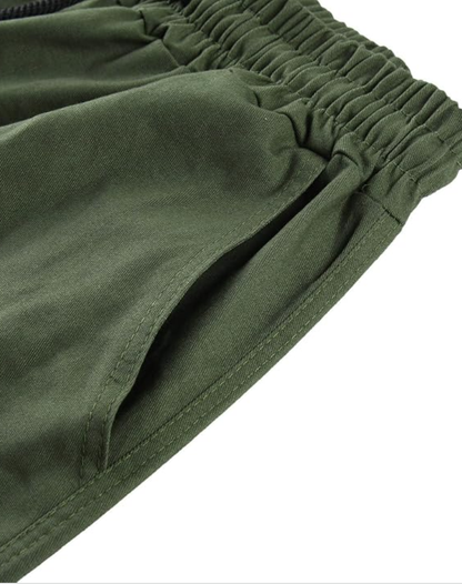 Nahaufnahme von elastischem Bund und seitlicher Eingrifftasche einer olivgrünen Hose mit sichtbaren Nähten