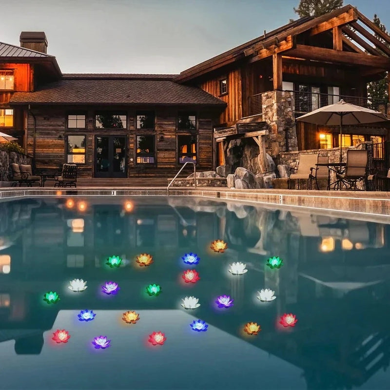 Viele bunt leuchtende Lotuslichter schwimmen abends auf einem Pool vor einem Holzhaus mit Terrasse 7