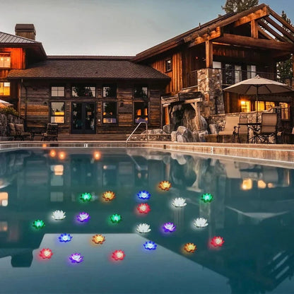 Viele bunt leuchtende Lotuslichter schwimmen abends auf einem Pool vor einem Holzhaus mit Terrasse 7