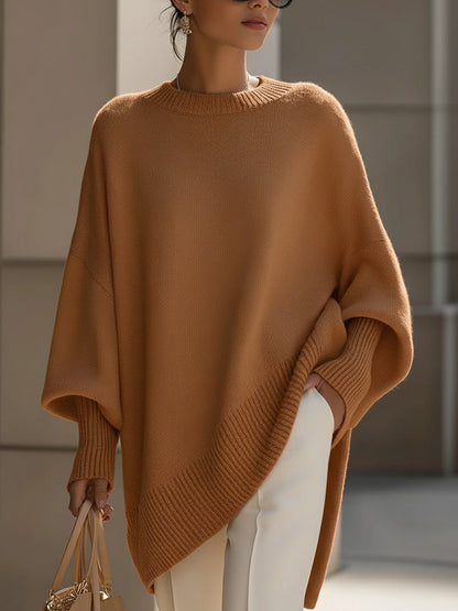 Camelfarbener Strickponcho in der Frontansicht, kombiniert mit weißer Hose und heller Handtasche 12