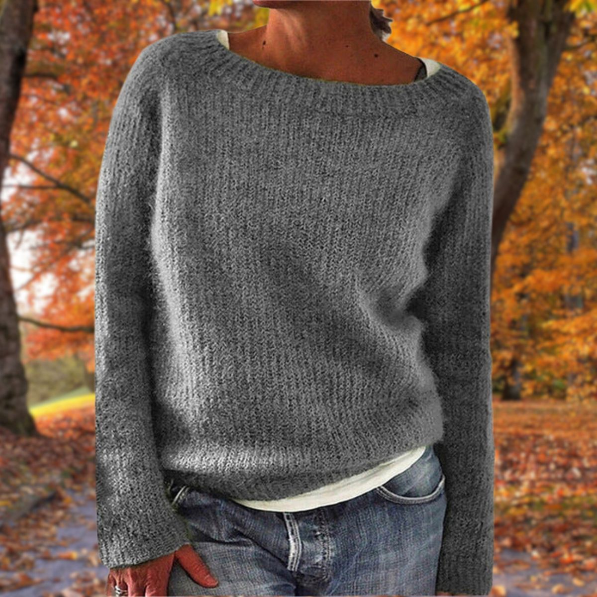 Grauer Strickpullover mit grobem Maschenbild, von einer Frau zu Jeans und weißem Shirt im Herbstpark getragen. 4
