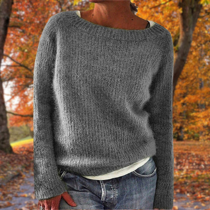 Grauer Strickpullover mit grobem Maschenbild, von einer Frau zu Jeans und weißem Shirt im Herbstpark getragen. 4
