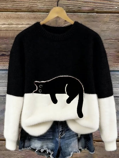 Schwarz-weißer Flauschpullover mit schwarzer Katze auf Kleiderbügel vor Holzwand, darunter Jeansshorts 6