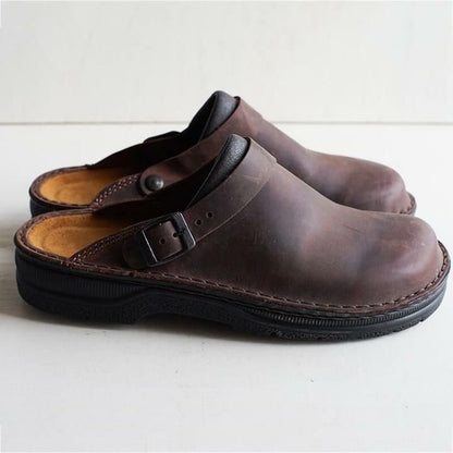 Seitenansicht eines dunkelbraunen Leder-Clogs mit Schnalle, Wildleder-Fußbett und dicker schwarzer Sohle auf hellem 4