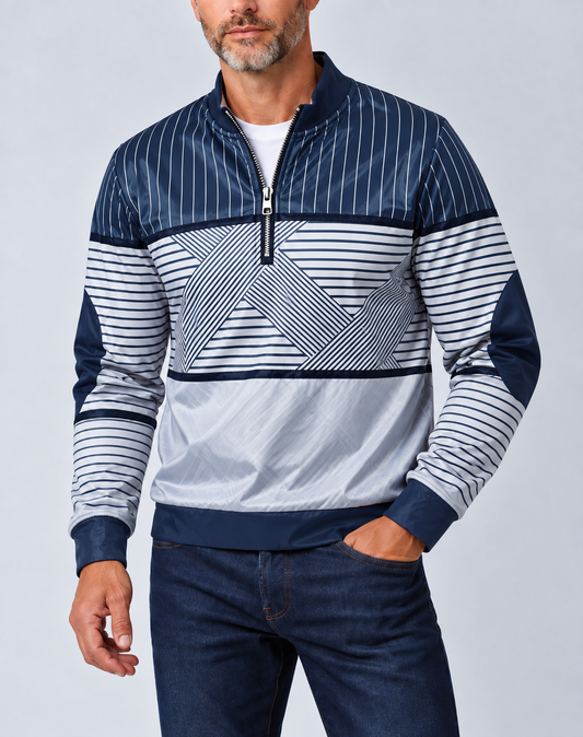 Mann mit grauem Bart trägt den marineblau-weiß gestreiften Pullover mit halbem Reißverschluss zu dunkler Jeans, Hand in der Hosentasche. 1