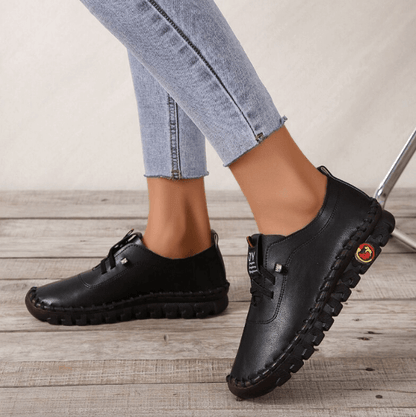 Schwarze Damen-Ledersneaker, bequem, rutschfest, modisch, auf Holzfußboden.