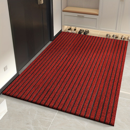 Rote Fußmatte mit dunklen Längsstreifen vor einer Garderobe auf Fliesenboden.