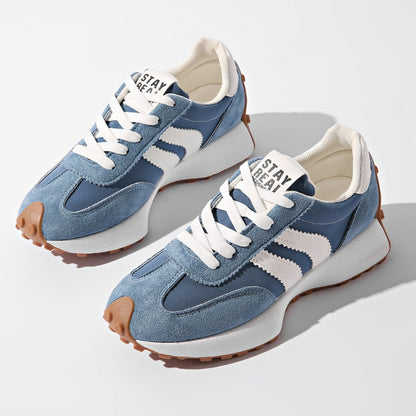 Paar blaue Wildleder-Sneaker mit weißen Streifen und Karamellsohle, von oben vor hellem Hintergrund fotografiert 2