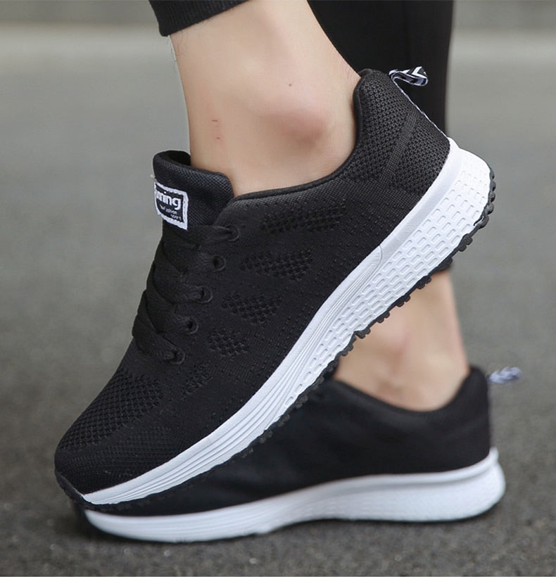 Schwarze Sportschuhe mit weißer Sohle, atmungsaktives Mesh, ideal für Laufen und Fitness.