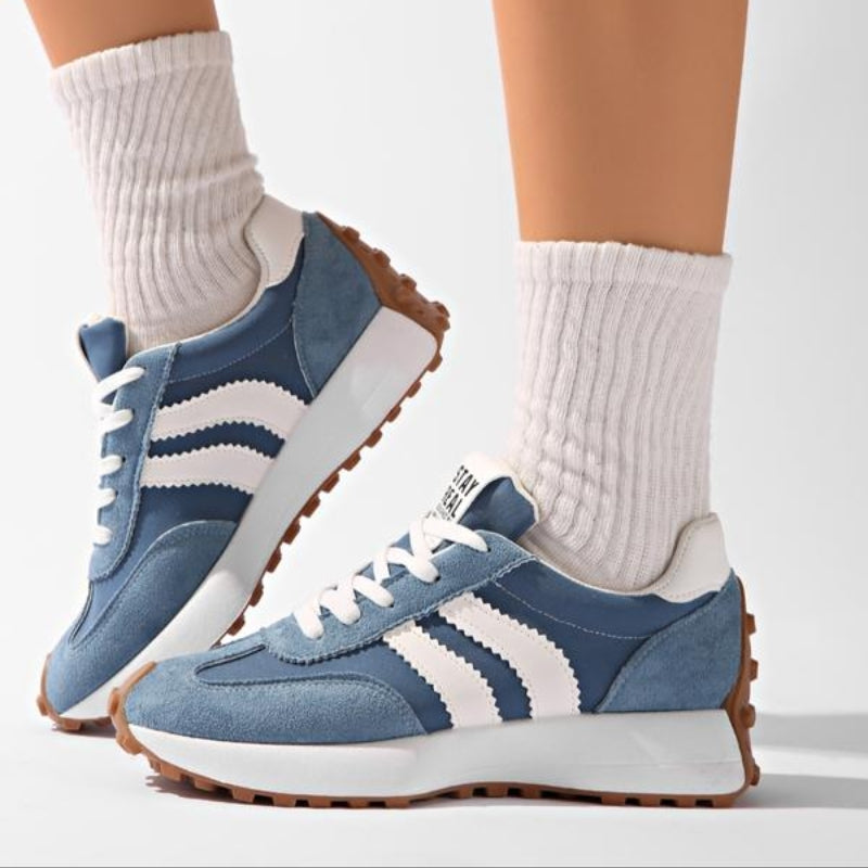 Blaue Sneaker mit weißen Streifen, getragen mit weißen Rippensocken, ein Fuß angehoben, Seitenansicht der Sohle 8